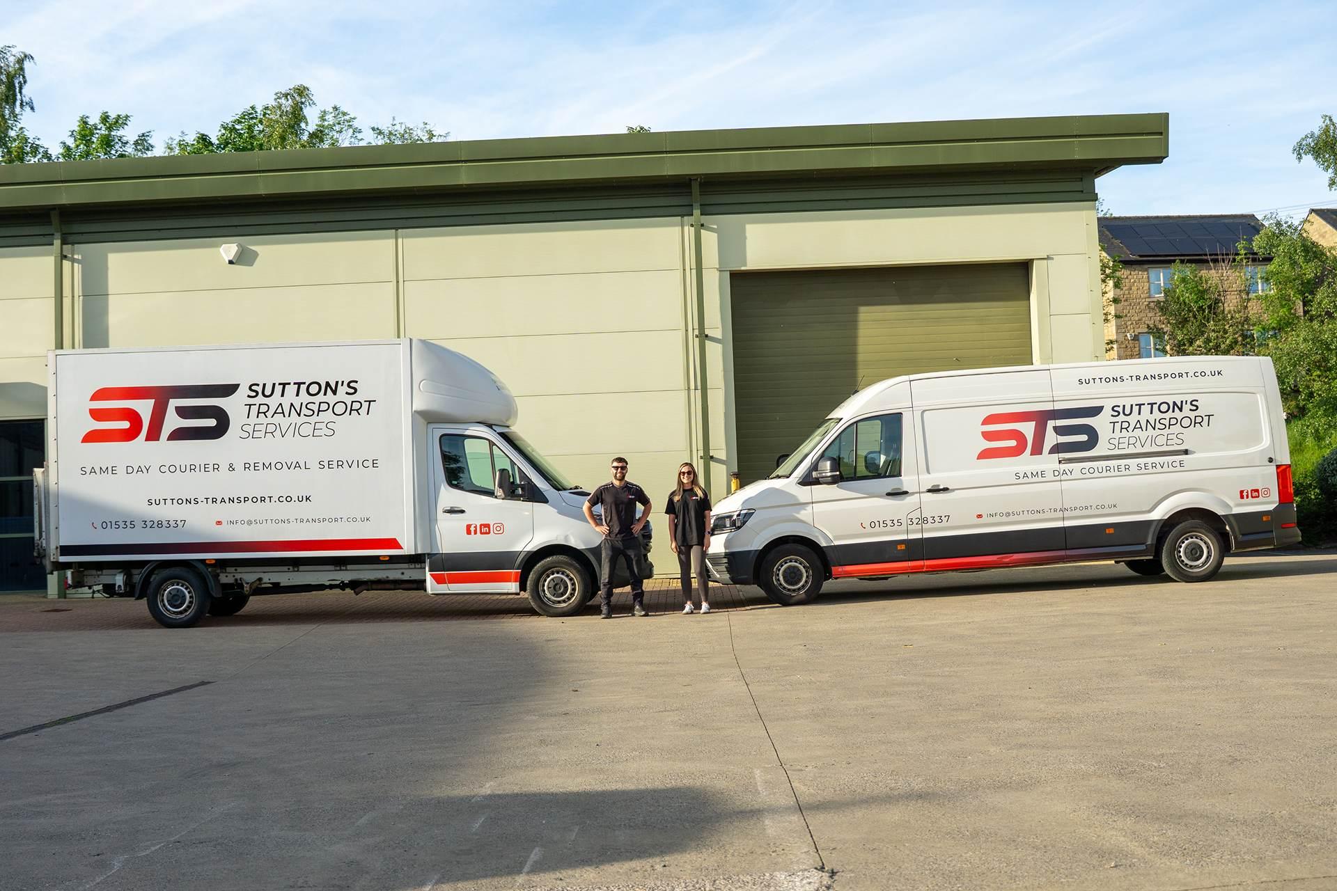 Two vans facing each other from the side with people stood in front